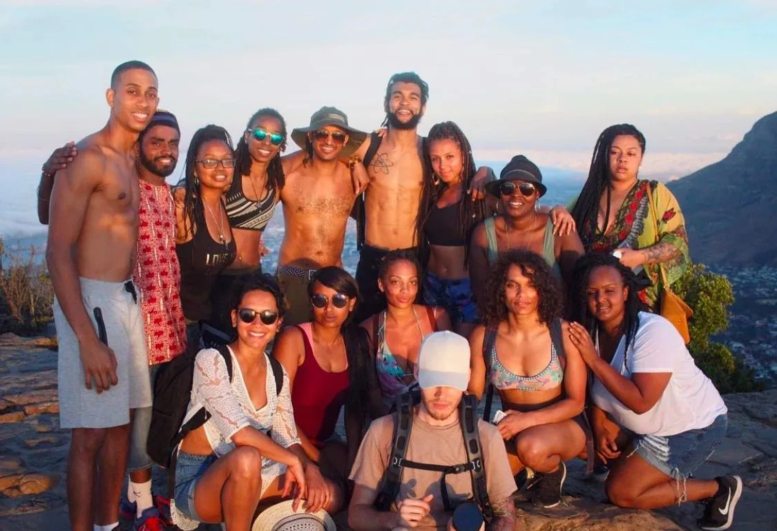 A large group smiling together outdoors at sunset.