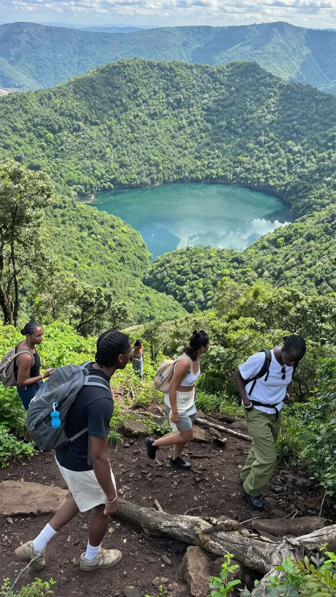 A group walking together outdoors dressed in white clothing and woven shawls, one woman smiling.